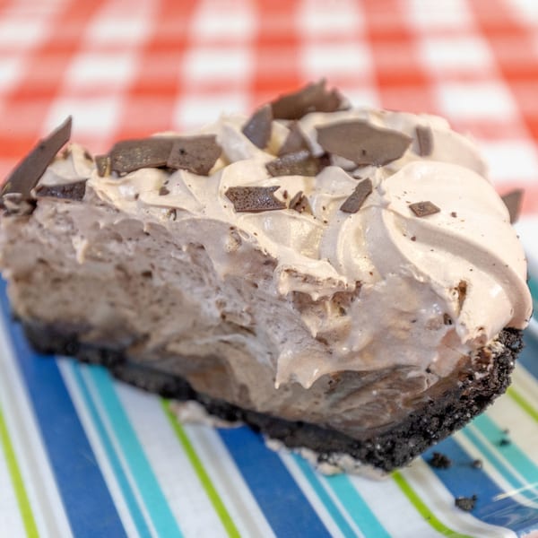 A slice of chocolate cream pie with chocolate shavings on a striped plate.